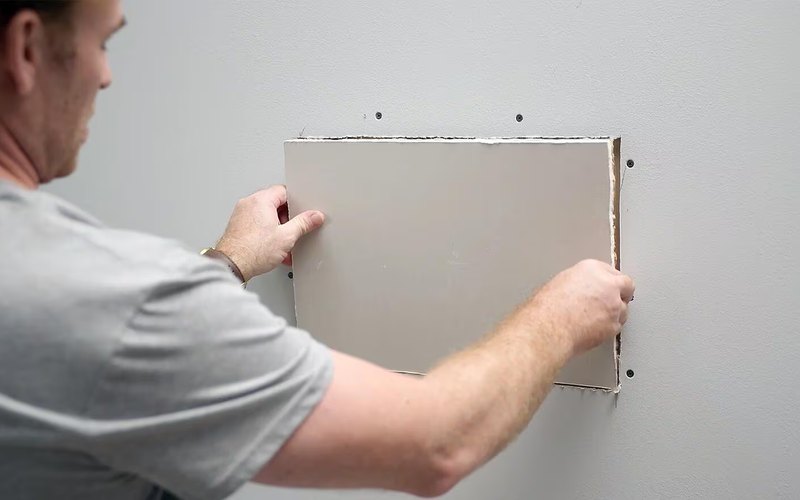 Drywall patch being installed before paint