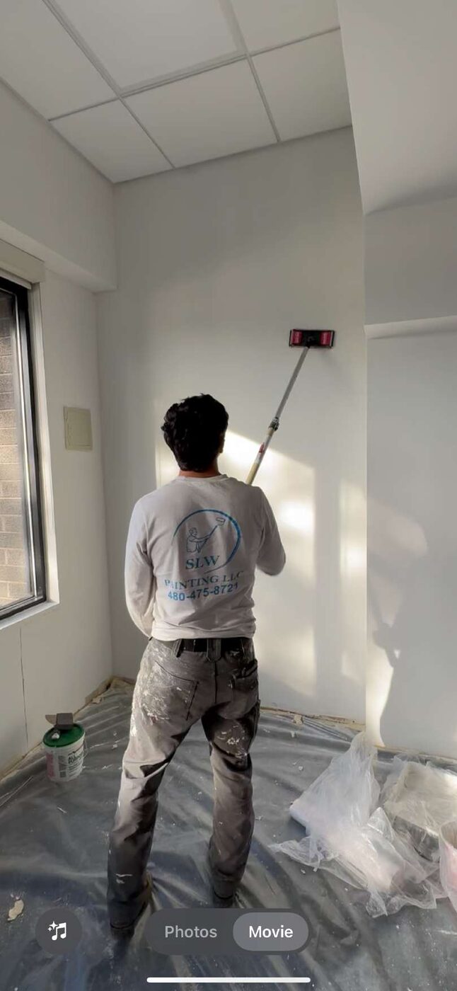 SLW Painting crew member rolling a wall with an SLW-branded shirt